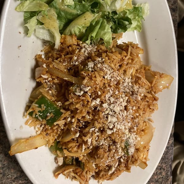 Indian rice dish with vegetables and nuts, served with a side of green salad.
